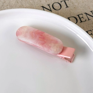 Pink marble pattern resin hair clip on a white plate with aesthetic linen background