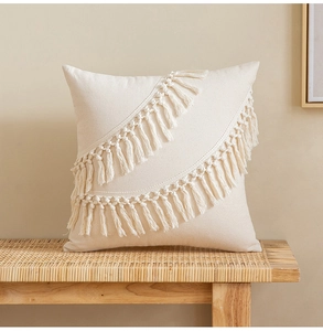Macro detail of bohemian cream cushion cover featuring woven tassels and textured fabric