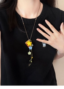 Detail view of colorful acrylic star charms and vintage pendant on a brown cord necklace