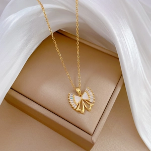 Detail of gold bow necklace pendant with white enamel and sparkling zircon stones