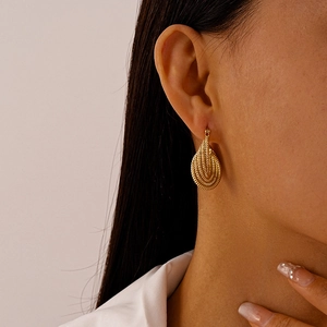 Detail view of gold pear-shaped drop earrings with a textured multilayered spiral design