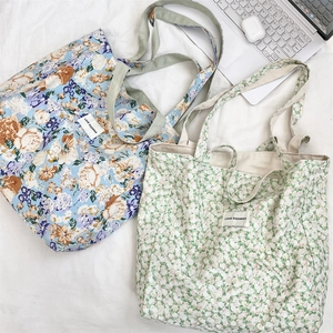 Flat lay detail of floral canvas tote bags with blue and white patterns on white fabric