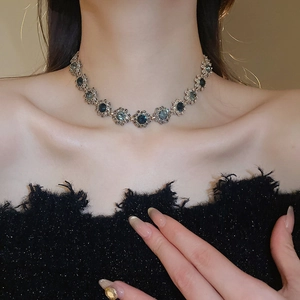 Close-up of vintage flower necklace with silver metal and deep blue gemstones on a model