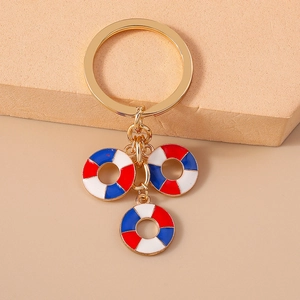 Close-up of golden metal keychain featuring three red, white, and blue lifebuoy charms