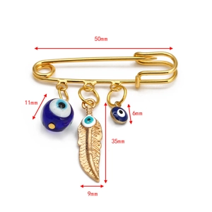 Detailed view of the 50mm gold evil eye safety pin brooch with feather and bead charms