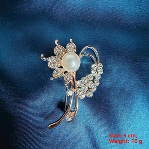 Detail of camellia brooch with white faux pearl and rhinestones on blue silk background