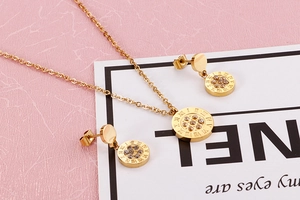 Detailed view of gold necklace and earrings set with Roman numerals and crystals