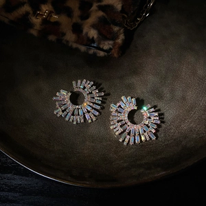 Macro shot of fan-shaped fan gold earrings with colorful rhinestones on dark background
