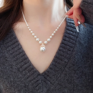 Gros plan du collier plaqué or avec pendentif perle ronde et petits détails en diamant