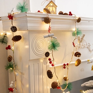 Pine cone Christmas garland with red berries and LED lights on a white mantelpiece