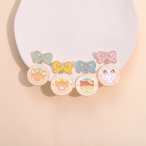 Set of four cartoon animal enamel pins with colorful bows on a white porcelain plate