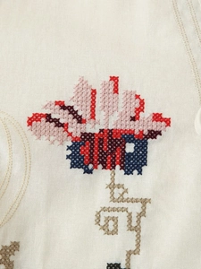 Gros plan d'une broderie florale complexe au point de croix sur tissu de robe en coton-lin
