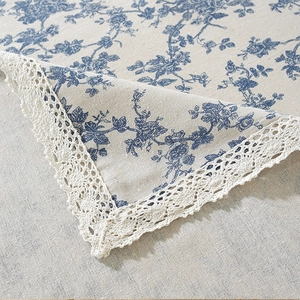 Macro view of vintage blue floral linen tablecloth with white lace edge trim details