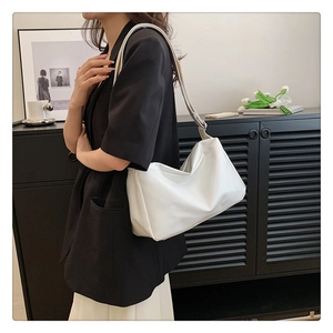 Minimalist white faux leather tote bag worn as a shoulder bag for office commuting