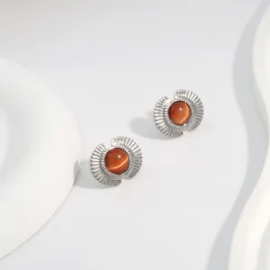 Detailed macro view of retro fan-shaped earrings with amber cat-eye stone inlay