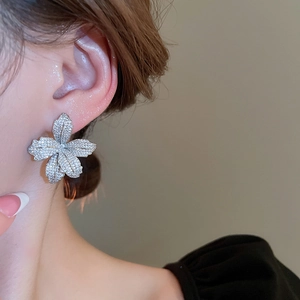 Close-up detail of silver floral stud earring with sparkling crystals on a model's ear