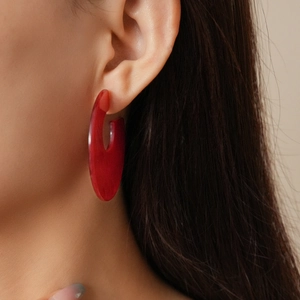 Close-up of a large red translucent acrylic C-shaped earring on a model profile