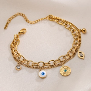 Gold-plated double-layer bracelet with evil eye charms on a soft beige fabric background