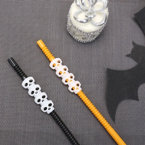 Close-up of Halloween pumpkin straws with white skull decorations in orange and black