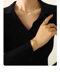 Set collana e bracciale a maglia piatta a serpente dorata con anelli su modella