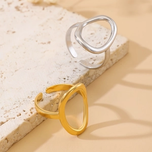 Detailed view of hollow oval rings in gold and silver finish on stone texture background