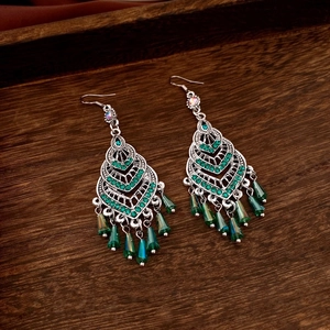 Detailed shot of silver vintage heart earrings with green crystal tassels and rhinestones