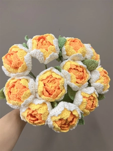 Close-up of hand-held handmade crochet peony bouquet in orange, yellow and white colors