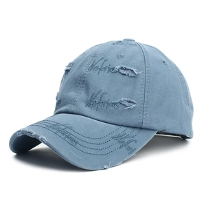 Detail view of vintage grey-blue baseball cap with distressed holes and Notorious embroidery