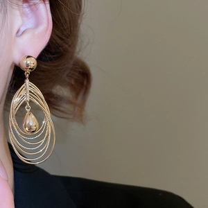 Macro shot of 18k gold plated multi-layer oval hoops with a polished metal teardrop charm