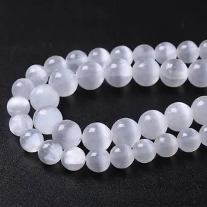 Polished white cat eye selenite beads for DIY jewelry making on black background