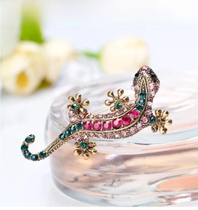 Macro shot of lizard brooch featuring vibrant pink and green rhinestones in golden alloy