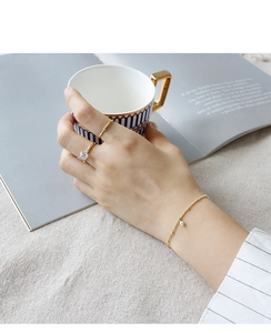Close-up of S925 silver gold rings and pearl bracelet on model hand in cozy setting
