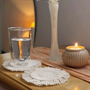 Handwoven Nordic cotton coaster in beige with round tassel fringe on a wooden table