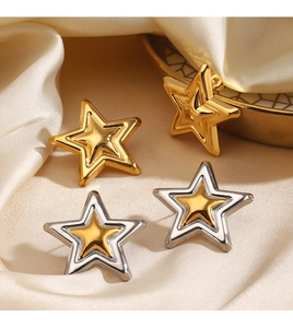 Detailed view of gold and silver star stud earrings on elegant silk fabric background