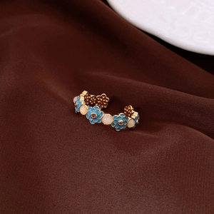 Close-up of vintage gold ring with blue enamel flowers and pink cat eye stones