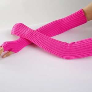 Detail of bright pink ribbed knit arm warmers with thumb holes on model's crossed arms