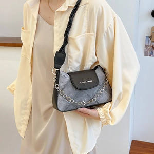 Denim textured underarm bag with metal chain and wide strap worn by a model