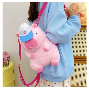 Detailed view of a cute pink plush pig crossbody bag worn by a model in a cozy setting