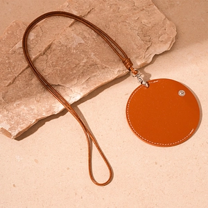 Close-up of brown faux leather round pendant with braided lanyard on stone texture