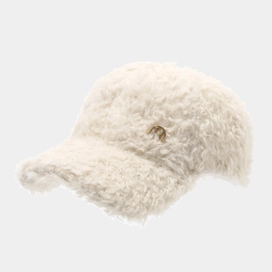 Detail der cremefarbenen Sherpa-Cap mit goldenem H-Buchstaben und kleinen Diamanten