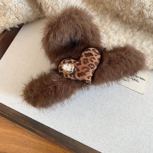 Detail of plush brown claw clip featuring a leopard heart and crystal accent