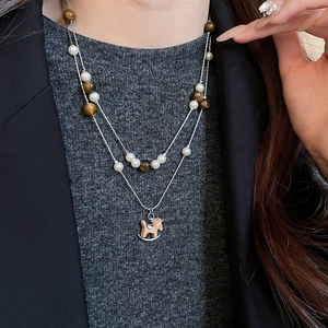 Détail d'un collier multicouche avec pierres œil de tigre, perles et pendentif cheval en bois