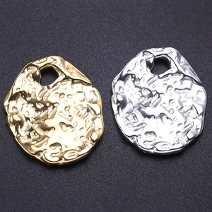 Detail of irregular hammer-textured oval pendants in gold and silver stainless steel