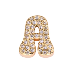 Macro detail of cursive letter A pendant with sparkling gold plating and zircon inlay