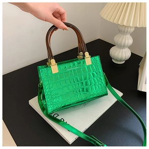 Detail of green faux crocodile skin handbag with stylish amber resin handle in a chic setting