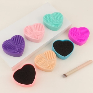 Close-up of heart-shaped silicone makeup brush cleaning mats and dry sponges with varied textures