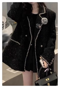 Detail of camellia flower brooches on a black tweed jacket with elegant metal chain trim