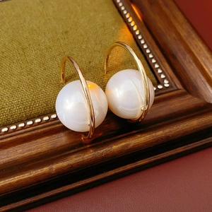 Close-up of elegant gold C-shaped earrings with large white pearls on a vintage frame