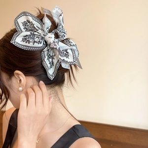 Detail of vintage paisley pattern on a large bow hair claw clip worn by a model
