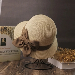 Straw sun hat with a brown linen bow and a ribbon on a vintage aesthetic background